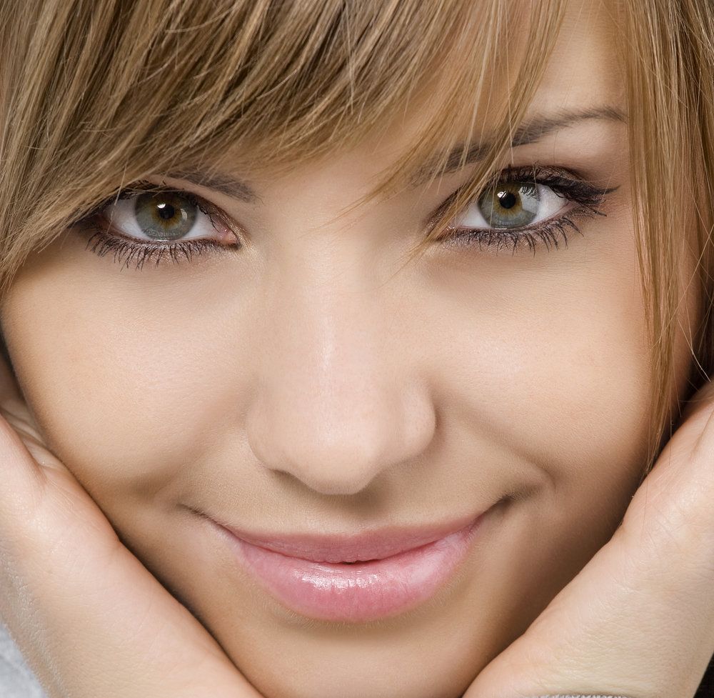 Attractive, smiling woman holding hands to cheeks