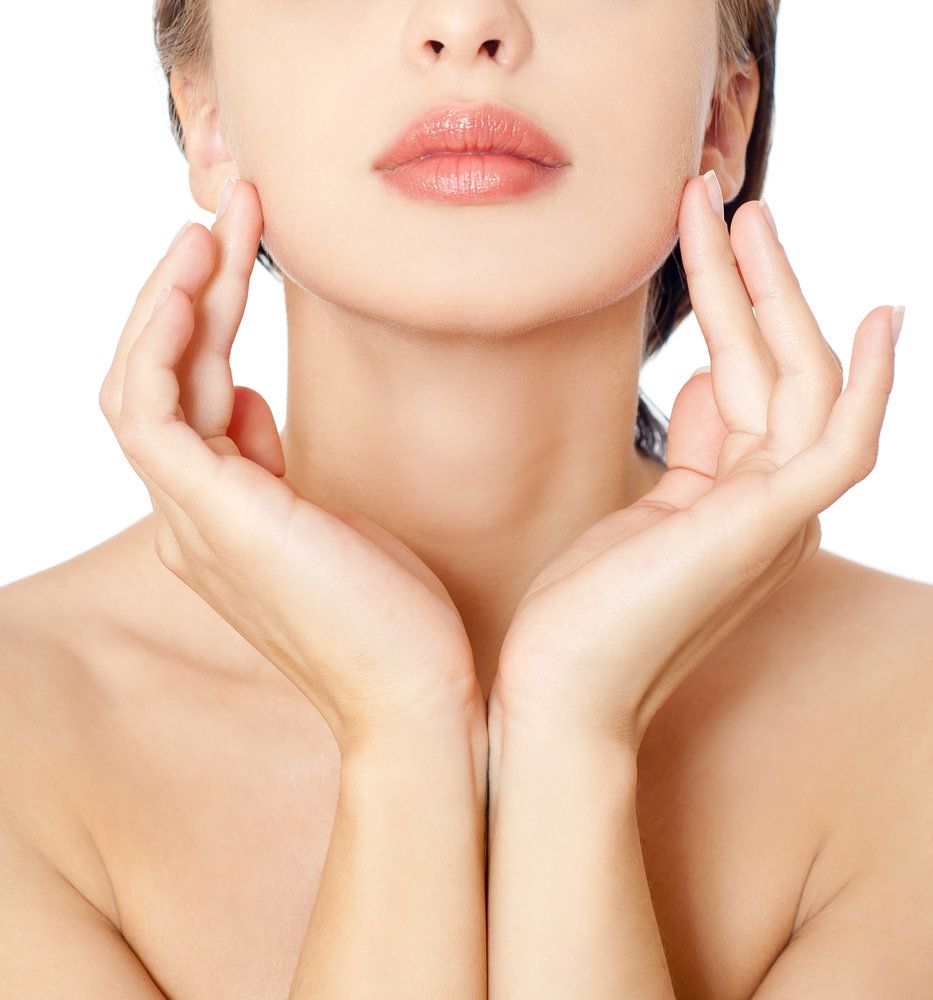 Close view of lower half of a young woman's face, hands touching her jaw